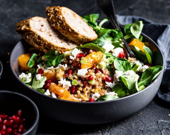 Grain bowl with spinach, grains and fruit in a slate gray bowl on a slate background