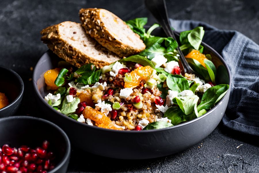 Grain bowl with spinach, grains and fruit in a slate gray bowl on a slate background